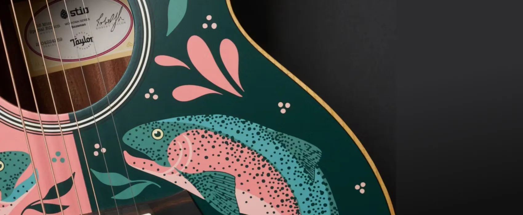 Hero closeup of a stio x taylor guitars guitar featuring a pink and green fish
